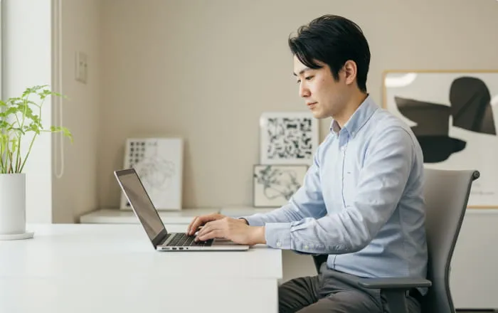 パソコンを使って作業をする男性が、助成金申請サポートについて考えている様子